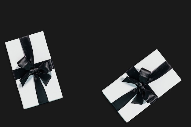 Bovenaanzicht van twee geschenkdozen met een lint op zwarte achtergrond met kopieerruimte