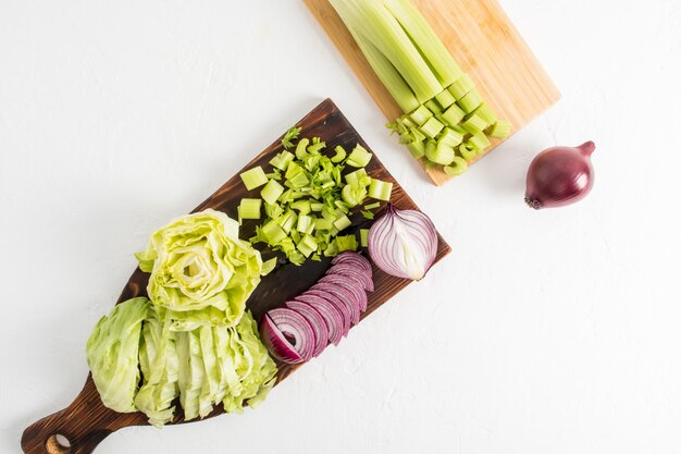 Bovenaanzicht van twee houten keukenplanken met groenten erop gesneden voor salade het concept van gezond eten vitamines witte achtergrond