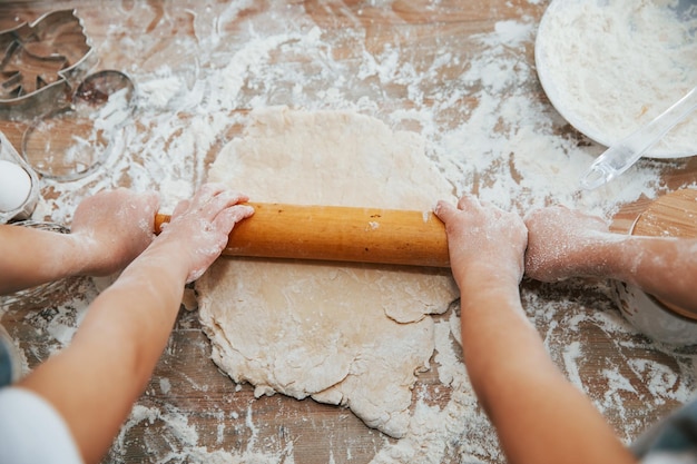 Bovenaanzicht van twee kleine meisjeshanden die kneden met gereedschap op tafel voorbereiden