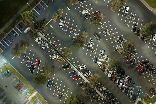 Bovenaanzicht van veel auto's die 's nachts geparkeerd staan op een helder verlichte parkeerplaats voor een kruidenierswinkelcentrum Concept van consumentisme en markteconomie