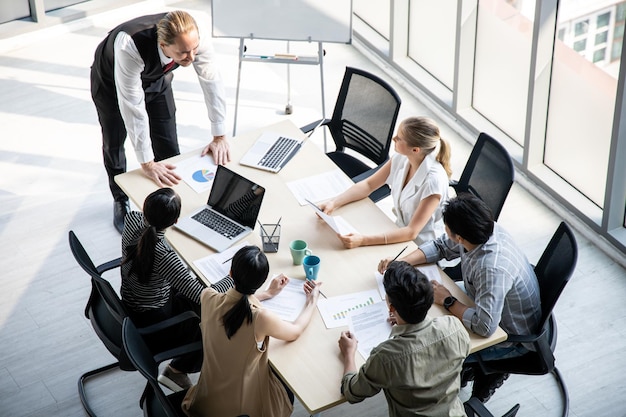 Bovenaanzicht van vergaderingen en consultaties van zakenmensen in de vergaderruimte van het bedrijf. Conferentie om de voortgang van de organisatie te analyseren en te vinden.