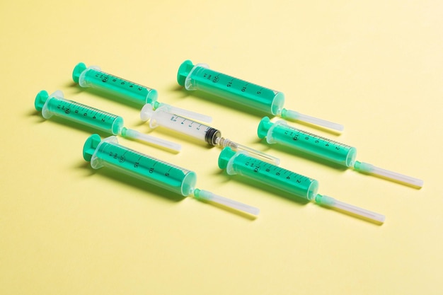 Bovenaanzicht van verschillende spuiten op gele achtergrond Medisch injectieconcept met kopieerruimte