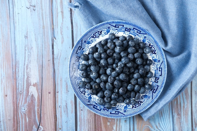 Bovenaanzicht van verse blauwe bes op een bord op tafel