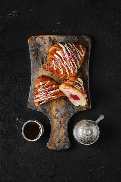 Bovenaanzicht van verse croissant met frambozenvulling op houten serveerplank