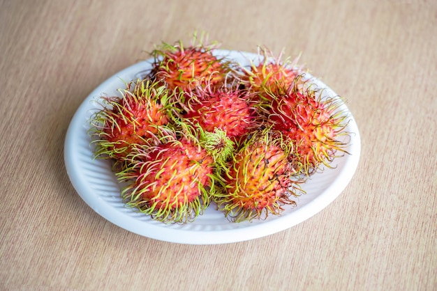 Bovenaanzicht van verse rijpe rambutans op plaat op houten achtergrond