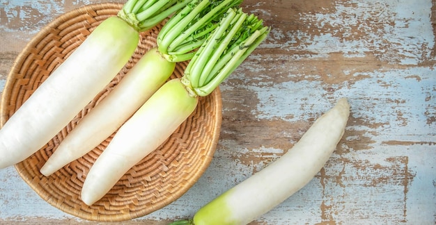 Bovenaanzicht van verse witte radijs groente in een mand geplaatst op een oude houten backgroundraw radish