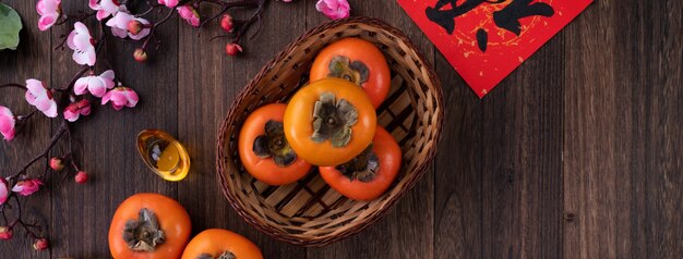 Bovenaanzicht van verse zoete kaki kaki met bladeren op houten tafel voor Chinese nieuwe maanjaar concept, het woord betekent zegen komt eraan.