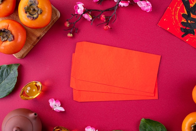 Bovenaanzicht van verse zoete kaki kaki met bladeren op rode tafel achtergrond voor Chinees maannieuw jaar fruit ontwerpconcept, het woord betekent dat de lente eraan komt.