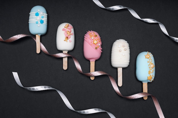 Foto bovenaanzicht van versierde cake pops ijsjes op zwarte achtergrond