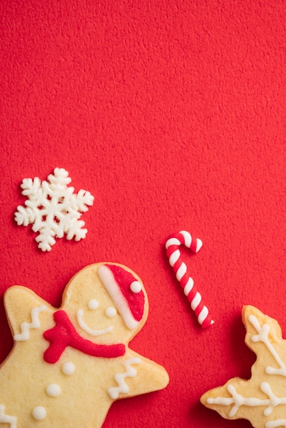 Bovenaanzicht van versierde peperkoek kerstkoekjes op rode tabelachtergrond met kopieerruimte, concept van vakantieviering.