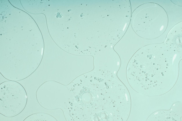 Bovenaanzicht van vloeibare cosmeticagel met bubbelstructuur op pastelcyaanachtergrond