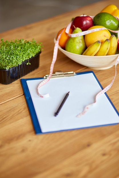 Foto bovenaanzicht van voedingsdeskundige, diëtist werkplek met meetlint en kom met gezonde groenten en fruit