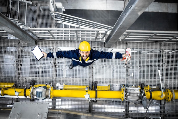 Bovenaanzicht van vrolijke raffinaderijarbeider die bij de gasleiding staat en omhoog kijkt