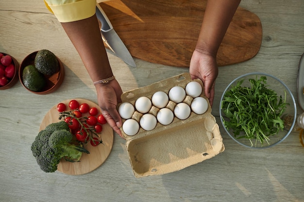 Bovenaanzicht van vrouw die groenten en eieren klaarmaakt om salade aan tafel in de keuken te bereiden