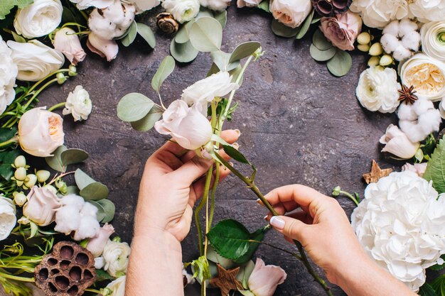 Bovenaanzicht van vrouw handen met bloemen. Bloemist maakt stijlvolle bruiloftscompositie, floristisch ontwerp