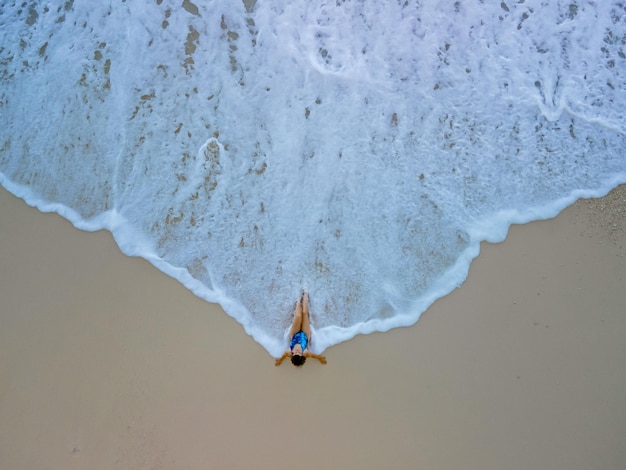 Bovenaanzicht van vrouw in blauwe zwembroek op zee strand mooie golven