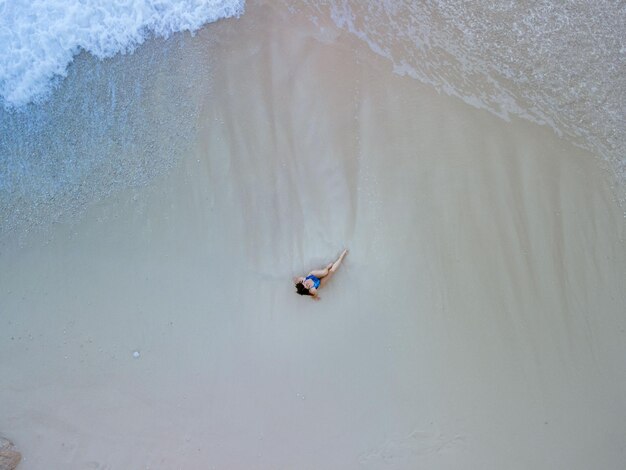 Bovenaanzicht van vrouw in blauwe zwembroek op zee strand