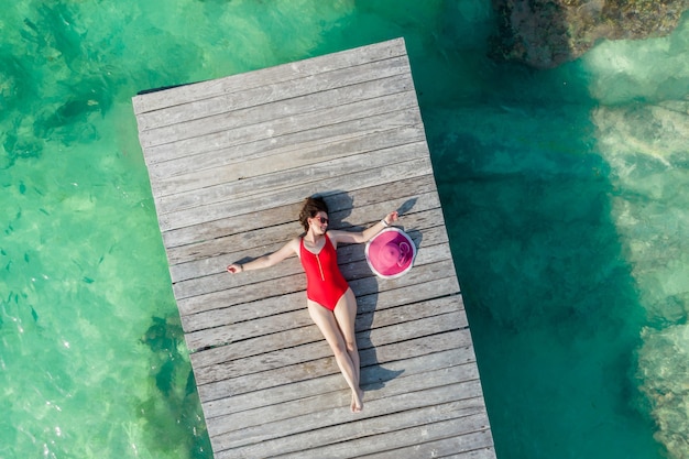 Bovenaanzicht van vrouw liggend op houten pier op zonnige zomerdag in cancun mexico jonge sexy vrouw in