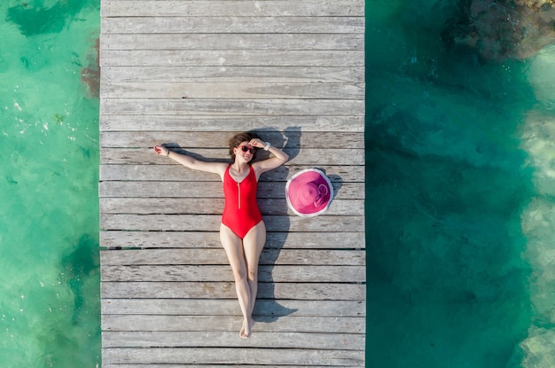 Bovenaanzicht van vrouw liggend op houten pier op zonnige zomerdag in cancun mexico jonge sexy vrouw in
