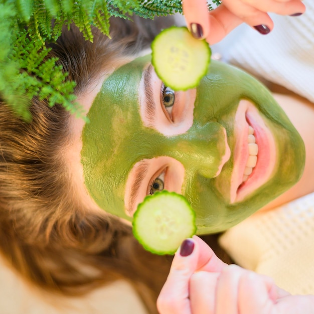 Bovenaanzicht van vrouw met gezichtsmasker op plakjes komkommer