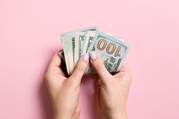 Bovenaanzicht van vrouwelijke hand met een pakje geld op kleurrijke achtergrond. Diverse dollars. Bedrijfsconcept. Liefdadigheid en tips concept