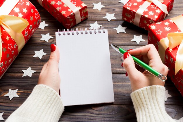 Bovenaanzicht van vrouwelijke hand schrijven in een notitieblok op houten Kerstmis.