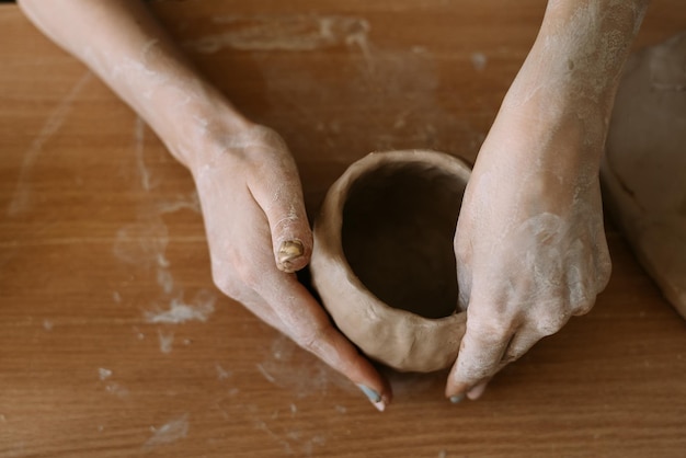 Bovenaanzicht van vrouwelijke handen beeldhouwen gebruiksvoorwerpen uit klei