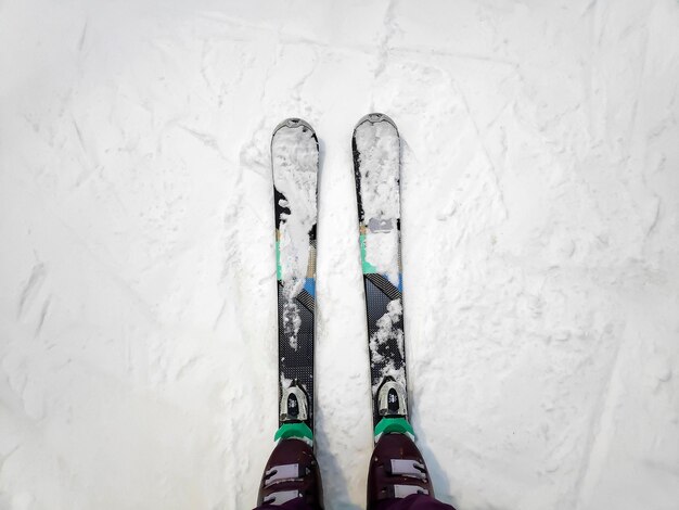 Bovenaanzicht van vrouwelijke womens benen in ski's op witte ijzige sneeuw oppervlak bergspoor achtergrond skiër benen op afdaling start rechte lijn rijen skihelling piste Winter actieve sport buiten concept