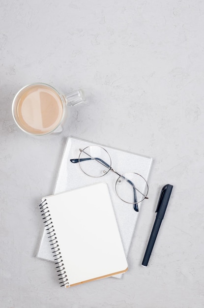 Bovenaanzicht van werktafel met blanco papier notebook kopje koffie en eyeglassess