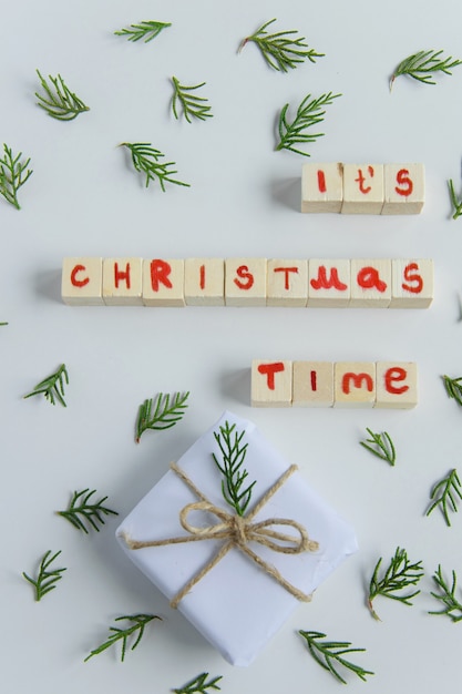 Bovenaanzicht van witte handgemaakte geschenkdoos met houten tekstletters van de kersttijd en verse sparrentak