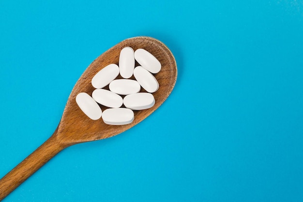 Bovenaanzicht van witte pillen in een houten lepel Medisch concept