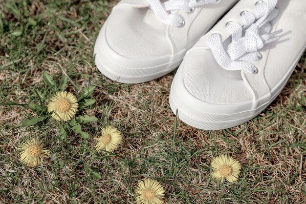 Bovenaanzicht van witte schoenen in een veld met witte bloemen Voeten in de natuur