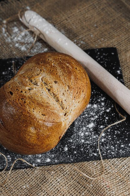 Bovenaanzicht van zelfgebakken brood met meel natuurlijke landbouwproducten Gezonde en smakelijke gebakjes Volkoren broodmeel Close-up donkere achtergrond
