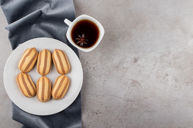 Bovenaanzicht van zelfgemaakte koekjes met kopje koffie op crème achtergrond.
