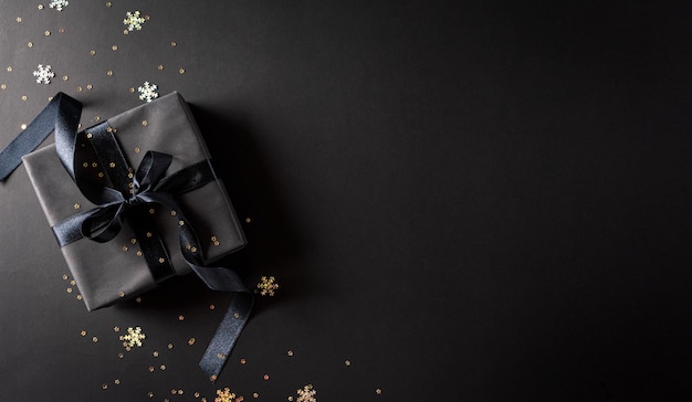 Bovenaanzicht van zwarte kerstcadeaudozen met zwart lint op zwarte achtergrond met kopieerruimte voor tekst Black Friday-compositie