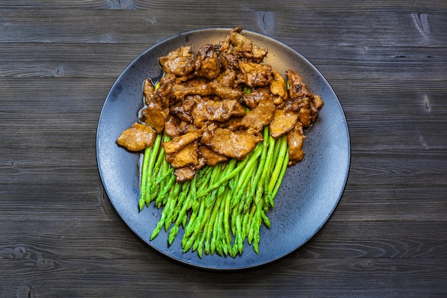 Bovenaanzicht van zwarte plaat met rundvlees en asperges