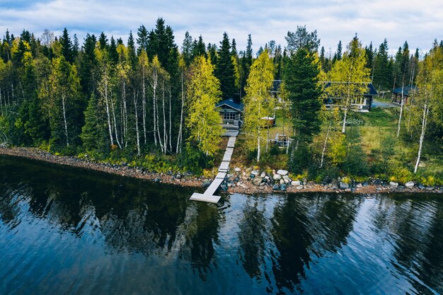 Bovenaanzicht vanuit de lucht van blokhut of huisje met sauna in het lentebos aan het meer op het platteland van Finland