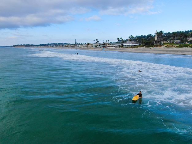 Bovenaanzicht vanuit de lucht van surfers die wachten op de golven in blauw water. Del Mar Beach, Californië, VS.