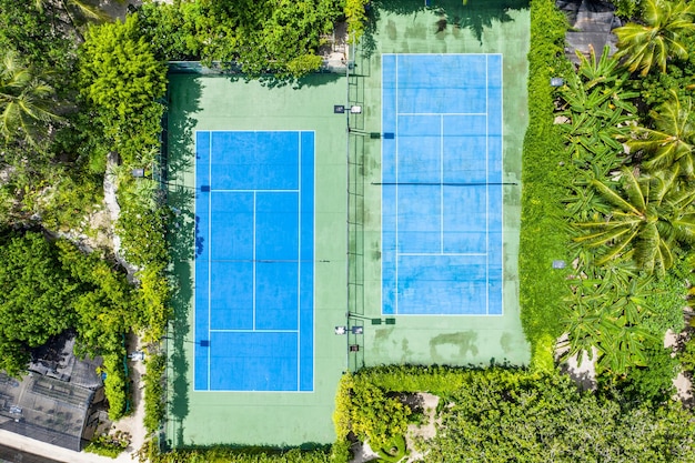 Bovenaanzicht vanuit de lucht van tennisbanen naast de palmbosjungle. Tropische outdoor recreatieve activiteit