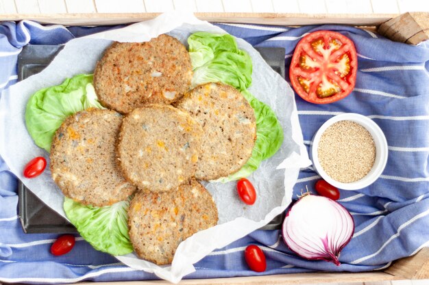 Bovenaanzicht Veggie quinoa burger met tomaat, kerstomaatjes, ui, komkommer, sla