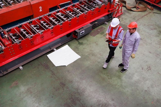 Bovenaanzicht vergadering fabrieksingenieur werknemer metalen plaat dak machine lopen en vergadering bij zware industrie productie fabrieksarbeider in veiligheidshelm bij fabriek industriële faciliteiten