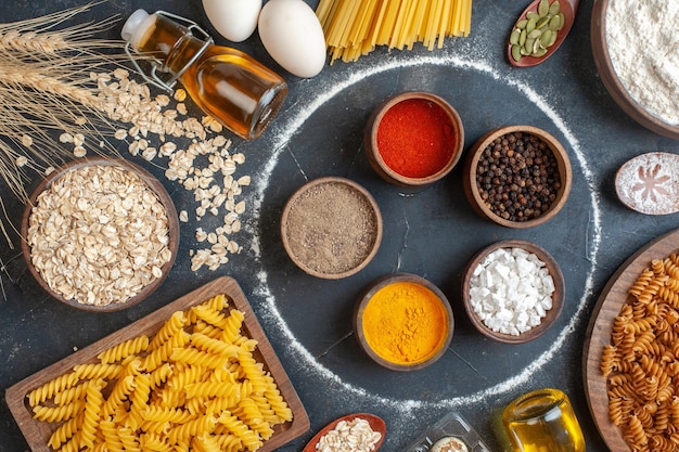 Bovenaanzicht verschillende smaakmakers met rauwe pasta-eieren en bloem op donkere achtergrondkleur deeg foto maaltijd keuken