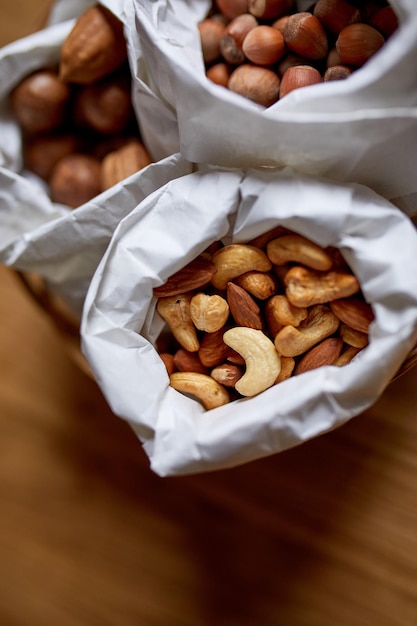 Bovenaanzicht Verschillende soorten noten op tafel in een papieren zak op houten achtergrond winkelen kruidenier concept noten levering Zero Waste Food Shopping Kopieer ruimte