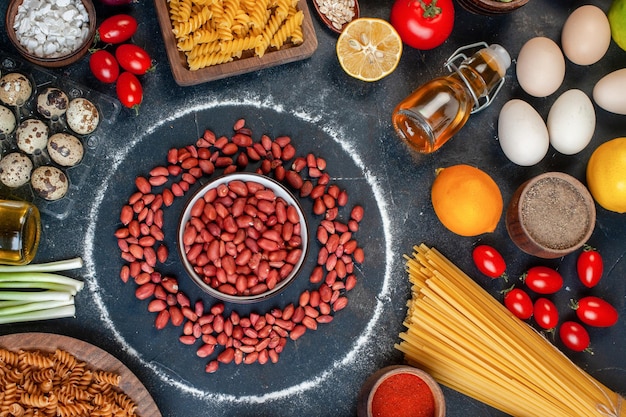 Bovenaanzicht verse pinda's in cirkel rond eieren groenten pasta en kruiderijen op donkere achtergrond foto kleur maaltijd gezondheid voedsel dieet