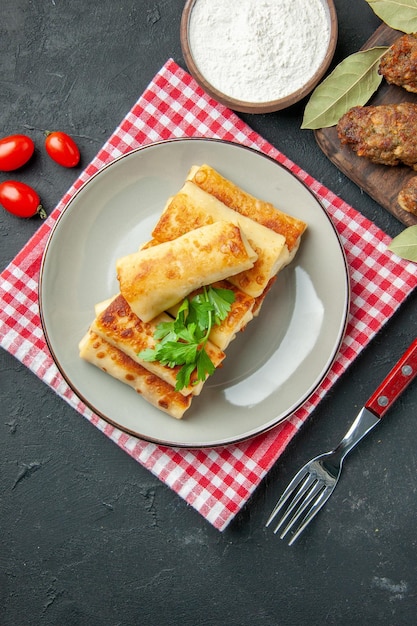 Bovenaanzicht vlees gevulde blini op ronde plaatvork cherrytomaatjes op tafel