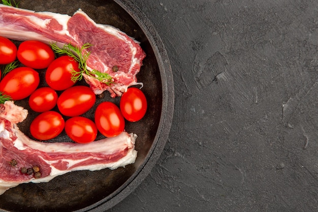 Bovenaanzicht vleesplakken met rode tomaten in pan op grijze achtergrond kip rauwe koe peper kleur vlees foto dier vrije ruimte