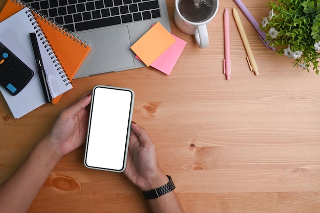 Bovenaanzicht vrouw met mobiele telefoon met lege display op houten bureau