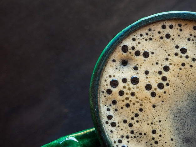 Bovenaanzicht warme koffie in groene kop op houten achtergrond