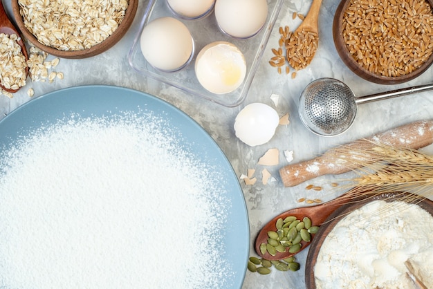 bovenaanzicht witte bloem met eieren rauwe granen en zaden op witte achtergrond deeg taart zaad melk cake kleur maïs