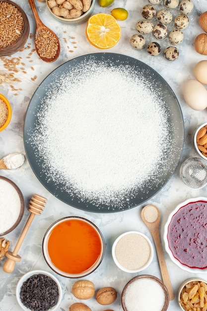 Foto bovenaanzicht witte bloem rond eieren zaden noten en gelei. taart cake jam ei deeg bakken fruit kleuren voedsel